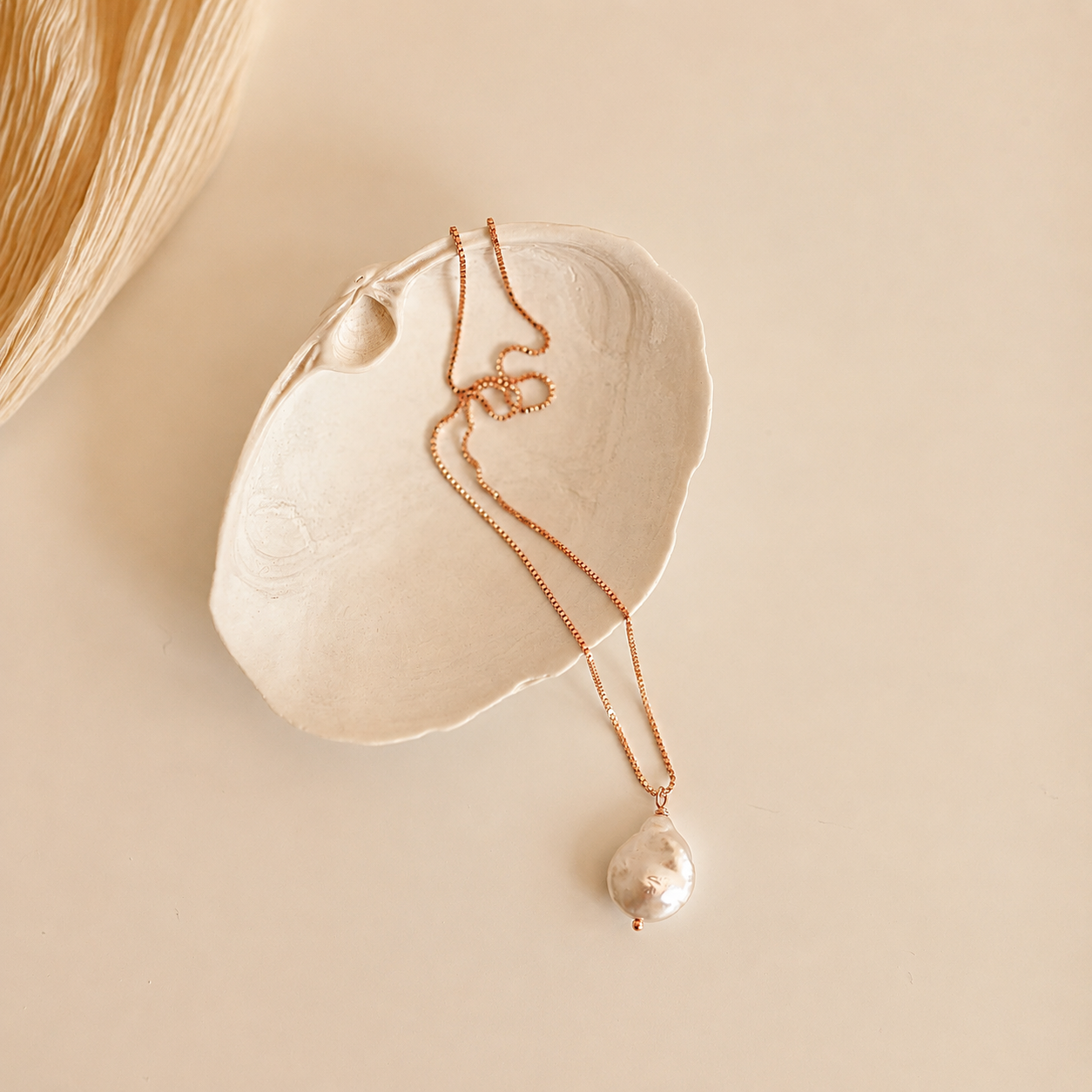 Pearl necklace with a pendant on a beige shell against a beige background